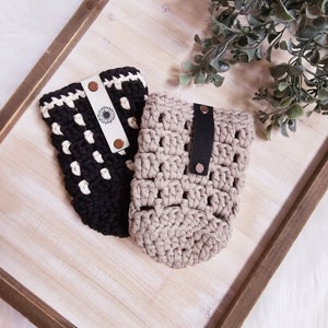 May include: Two crocheted cup holders with leather straps and metal rivets. One is black and white with a sunflower design, the other is beige.