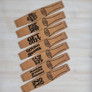May include: Seven wooden wristbands with black text. The text on the wristbands reads: "Let's spice things up", "hello pumpkin", "GET COZY", "GOURD geous", "Pick of the patch", "thankful grateful & blessed", "cozy vibes".