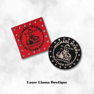 May include: Two leather patches featuring a black and white image of Michael Myers from the Halloween films. The text on the patches reads "Michael Myers Est. 1978 Always Fresh Butcher Shop". One patch is red and the other is black.