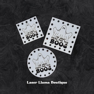 May include: Three white Halloween coasters featuring a ghost design and the phrase "I'M JUST HERE FOR THE BOOS." The coasters are square and circular, with black polka dots around the edges. Set against a dark, textured backdrop.