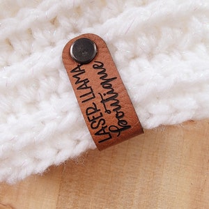 May include: A brown leather tag with a metal rivet. The tag is engraved with the text "LASER LLAMA" and "from Timmie".
