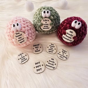 May include: Five crocheted plush balls with different sayings on wooden tags. The tags say "You found my sweet spot!" "Life's a treat: stay sweet!" "Drop me a line!" "OH Goody Goody Gumdrop!" and "Sugar, Spice & Everything Nice!"