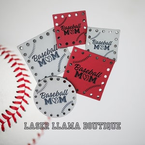 Peut inclure: Cinq formes en bois découpées au laser sur le thème du baseball. Les formes sont rouges et blanches avec du texte noir qui dit "Baseball Mom" et un cœur. Les formes sont décorées d'un motif de points de baseball et d'un graphique de batte et de balle de baseball.