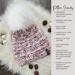 May include: A knit beanie with a large white faux fur pom-pom, featuring a variegated yarn pattern in shades of pink, white, and grey. A small dark tag is attached to the side. The text reads: Pattern Includes Advanced Beginner Friendly Directions, Written and Video Tutorials, Bulky Yarn Directions, Super Bulky Yarn Directions, Bonus Cup Cozy Pattern, Easy Repeating Design, Stash Buster Pattern, Works Up Quickly.