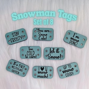 May include: A set of eight teal-colored snowman tags with various winter-themed phrases in black text. The tags include phrases like "Stay Frosty!" and "You are Snow Cute!" Each tag has two sets of holes for attaching.