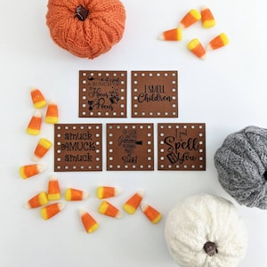May include: Six brown leather Halloween-themed gift tags with black text and white polka dots. The tags feature phrases like "It's just a bunch of Hocus Pocus", "I smell children", "Oh look another glorious morning makes me sick", and "I put a spell on you".