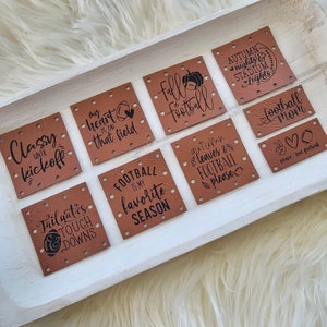 May include: Ten brown leather patches with black text and images. The patches feature football-themed sayings like "Classy Until Kickoff", "My Heart Is On That Field", "Fall & Football", "Tailgates & Touch Downs", "Football Is My Favorite Season", "Autumn Leaves & Football Please", "Peace Love Football", "Football Mom", and "Autumn Nights & Stadium Lights".
