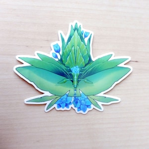 May include: A green leafy sticker with blue flowers. The sticker is shaped like a butterfly with its wings spread out.