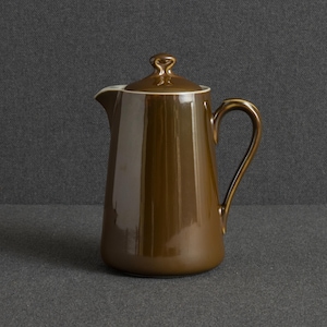May include: A glossy, dark brown ceramic coffee pot with a smooth, cylindrical body, a curved handle on the right side, a small pouring spout on the left, and a matching lid with a small, looped handle on top, featuring a clean, simple design.