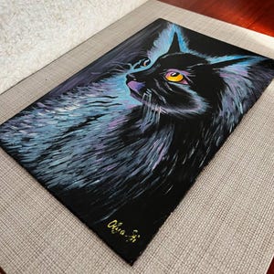 May include: A black cat with yellow eyes is painted on a black canvas. The cat's fur is painted with shades of blue and purple. The artist's signature, "Olivia-Ji", is in the bottom right corner of the painting.