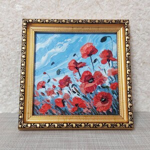 May include: A framed painting depicting a field of red poppies against a blue sky. The painting is executed in a loose, impressionistic style.