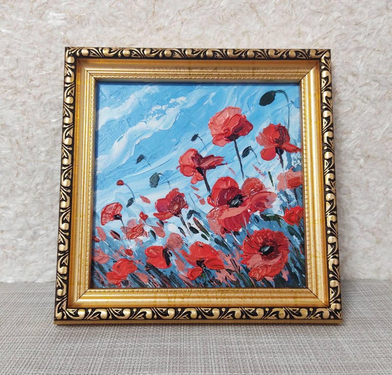 May include: A framed painting depicting a field of red poppies against a blue sky. The painting is executed in a loose, impressionistic style.