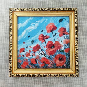 May include: A framed painting depicting red poppies against a blue sky with white clouds. The painting is executed in a loose, impressionistic style.