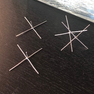 May include: Three silver metal star-shaped jewelry findings on a black surface.
