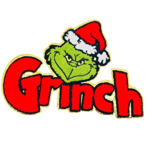 May include: A Christmas-themed Grinch design. The Grinch's green face is wearing a red Santa hat with white trim. The word "Grinch" is written in red, outlined in gold.