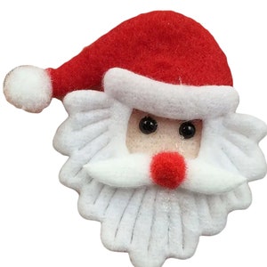 May include: A white felt Santa Claus face with a red felt hat, black eyes, and a red felt nose.