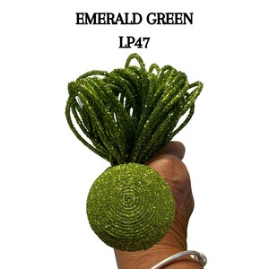 May include: Emerald green glitter cord, a spool of green sparkly string, with the text "LP47" printed above it.