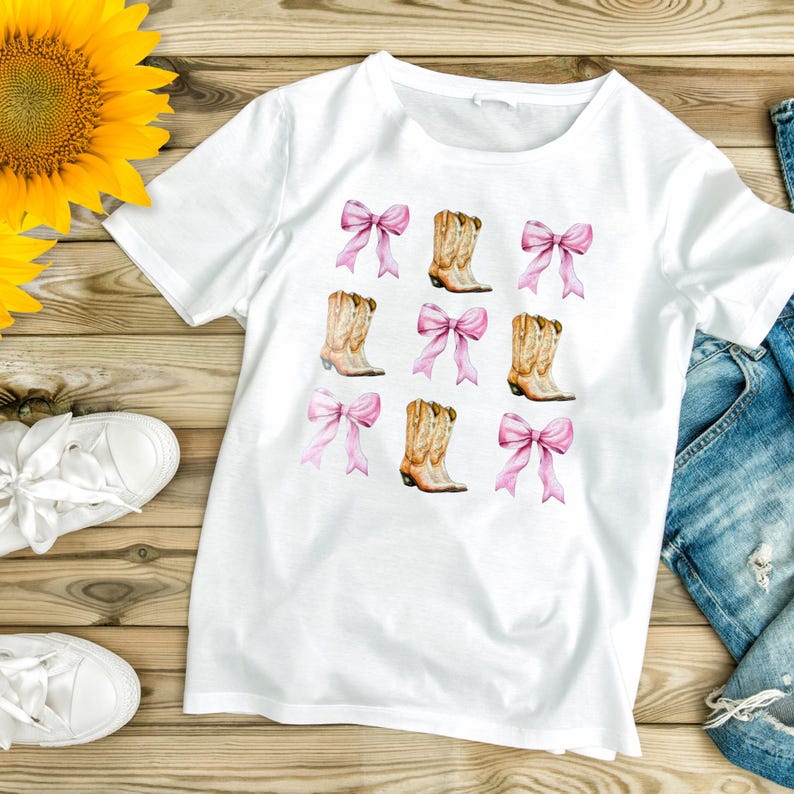 May include: White t-shirt featuring a repeating pattern of pink bows and cowboy boots. The boots are tan with brown accents. The bows are a soft pink color. The shirt is made of a soft, comfortable material.