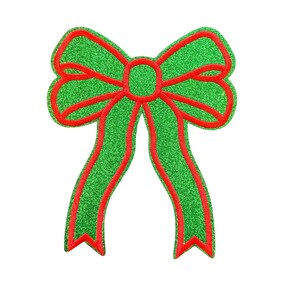 May include: A glittery green bow with red trim. The bow has a classic shape with two long, flowing tails. The design is festive and suitable for holiday decorations or gift wrapping.