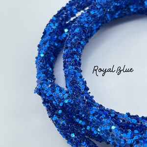 May include: Close-up of a spool of royal blue glitter cord. The cord is made of small, round glitter pieces.