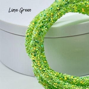 May include: Lime green glitter cord with iridescent shimmer. The cord is coiled and has a textured surface.
