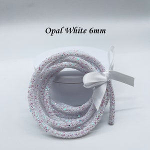 May include: A spool of white glitter cord with iridescent sparkle. The cord is 6mm thick and is wrapped around a white box with a white ribbon.