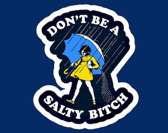 Puede incluir: Una pegatina con una ilustración retro de una persona con un vestido amarillo sosteniendo un paraguas azul bajo la lluvia. El texto dice "DON'T BE A SALTY BITCH" en blanco y negro.
