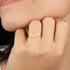 May include: A gold ring with the word "MAMA" spelled out in block letters.