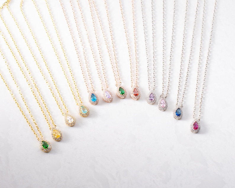 May include: A set of ten delicate necklaces with teardrop-shaped pendants featuring various coloured gemstones surrounded by clear cubic zirconia stones. The necklaces are available in gold, rose gold, and silver.