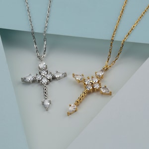 Puede incluir: Dos collares de plata y oro con colgantes de cruz adornados con piedras de circonita c&uacute;bica transparentes.