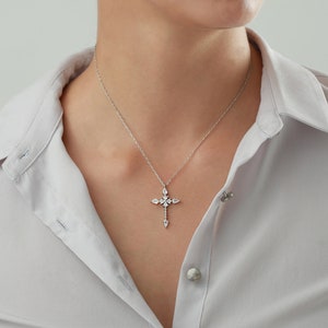Puede incluir: Un collar de cadena de plata con un colgante de cruz engastado con cristales.