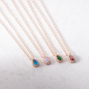May include: Five gold necklaces with teardrop-shaped pendants. Each pendant is set with a different coloured gemstone: blue, purple, green, and red.