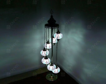 May include: A floor lamp with a spiral design and six round, colorful glass globes. The globes are lit and cast a warm glow.