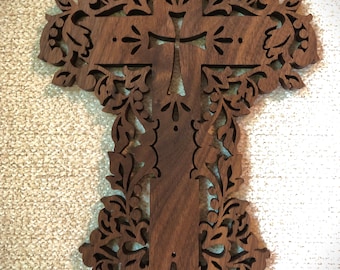 May include: A dark brown wooden cross with intricate floral carvings. The cross is made of walnut wood and has a distressed finish.