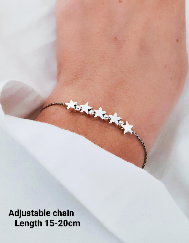 May include: A silver star charm bracelet with an adjustable chain. The chain is black and the stars are silver. The bracelet is adjustable from 15 to 20 centimeters in length. Adjustable chain Length 15-20cm