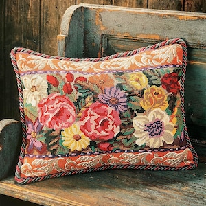Puede incluir: Una almohada con estampado floral en un esquema de colores rojo, verde y blanco. La almohada tiene un ribete de cuerda marrón y verde alrededor de los bordes.