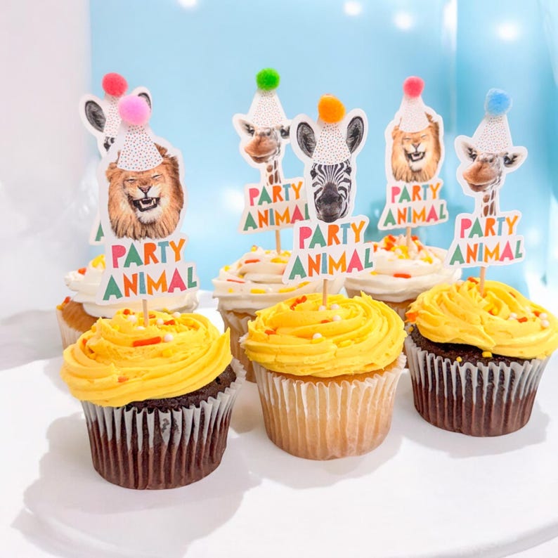 Puede incluir: Seis cupcakes con glaseado amarillo y chispas de colores. Cada cupcake tiene una decoraci&oacute;n tem&aacute;tica de animal de fiesta con un animal diferente: un le&oacute;n, una cebra, una jirafa y una jirafa. Las decoraciones tienen el texto "Party Animal".