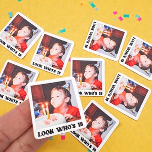 Op de afbeelding: Vierkante stickers met een foto van een persoon die kaarsjes op een verjaardagstaart uitblaast. De tekst LOOK WHO'S 18 staat in het zwart onderaan elke sticker met een witte rand. De stickers zijn gerangschikt op een gele achtergrond.