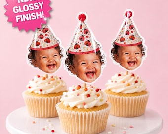 May include: Three cupcakes topped with custom photo cake toppers featuring a smiling child wearing a party hat with a ladybug pattern. The toppers have a glossy finish and a pink starburst graphic in the corner that reads NEW GLOSSY FINISH!