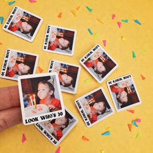 Könnte beinhalten: Quadratische Aufkleber mit einem Foto eines Kindes, das Kerzen auf einem Geburtstagskuchen auspustet. Der Text "LOOK WHO'S 30" ist darauf abgebildet. Sie liegen auf einer gelben Oberfläche mit bunten Konfetti.