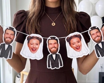 May include: A decorative banner featuring five individual cutouts strung together on a white cord. The cutouts alternate between a bearded person in a black tuxedo and a person with a winking expression wearing a white bridal veil.