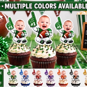 Op de afbeelding: Drie chocoladecupcakes met witte glazuur en groene hagelslag, elk voorzien van een papieren uitsparing van een baby in een groen football-shirt, met een bruine football en een groene schuimvinger met de tekst #1.
