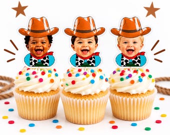Puede incluir: Tres cupcakes decorados con recortes de papel personalizados de bebés sonrientes con sombreros de vaquero naranjas y camisas azules con estampado de manchas de vaca en blanco y negro, sobre glaseado blanco con chispas redondas de colores.