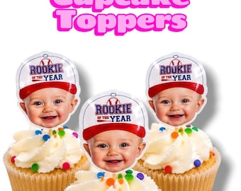 Puede incluir: Tres cupcakes con adornos circulares de papel que muestran a un bebé sonriente con una gorra de béisbol blanca y roja. La gorra muestra el texto Rookie of the Year con un gráfico de béisbol. El texto Cupcake Toppers aparece arriba.