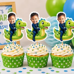 Puede incluir: Tres cupcakes en envoltorios verdes de lunares con glaseado blanco y adornos personalizados. Cada adorno muestra el rostro de un niño sobre un cuerpo de dibujos animados montando un dinosaurio inflable verde. Letrero con el texto LET'S ROAR AND SPLASH.