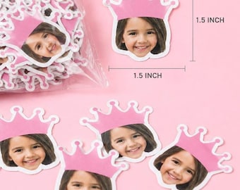 Pode incluir: Uma coleção de recortes de papel personalizados em forma de coroa rosa, cada um apresentando a fotografia do rosto de uma criança. Os recortes medem 1,5 polegadas por 1,5 polegadas, conforme indicado pelas linhas de medição visíveis.