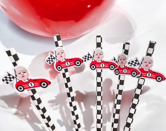 May include: Set of six black and white checkered paper straws with red race car toppers featuring a baby's face. Each topper has a number "1" on the car.