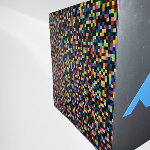 May include: A colourful box with a black and white pixelated design on one side and a blue mountain design on the other side.