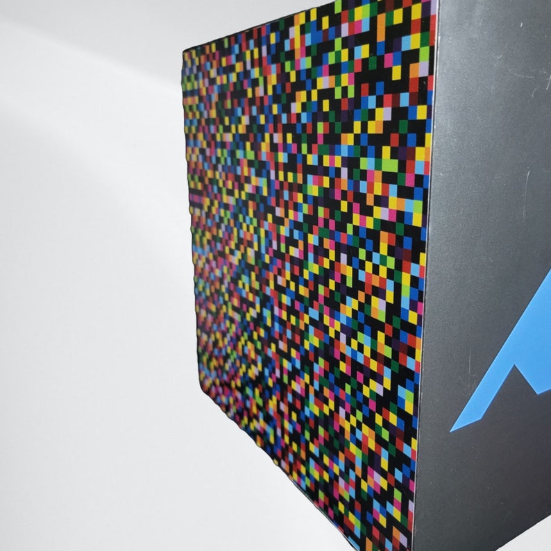 May include: A colourful box with a black and white pixelated design on one side and a blue mountain design on the other side.