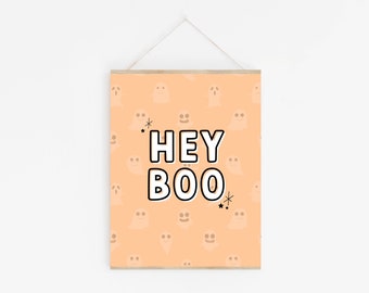 May include: A peach-colored printable sign with a pattern of white ghosts. The sign says "Hey Boo" in black and white letters with a white outline.